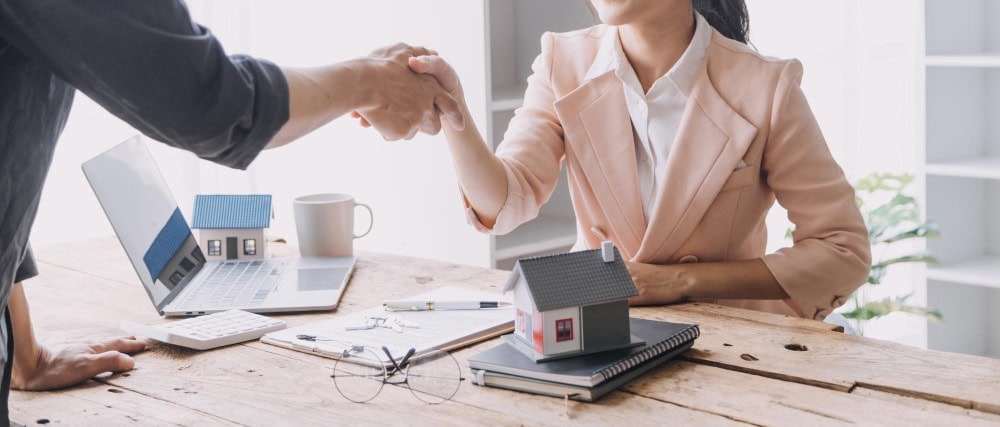 Professional real estate agent shaking hands with client.