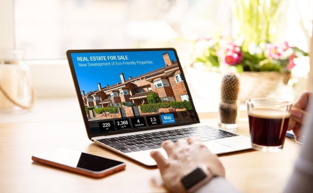 Person viewing property on laptop with real estate advertisement on screen.